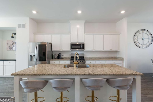 kitchen featuring an island with sink, white cabinetry, and stainless steel appliances