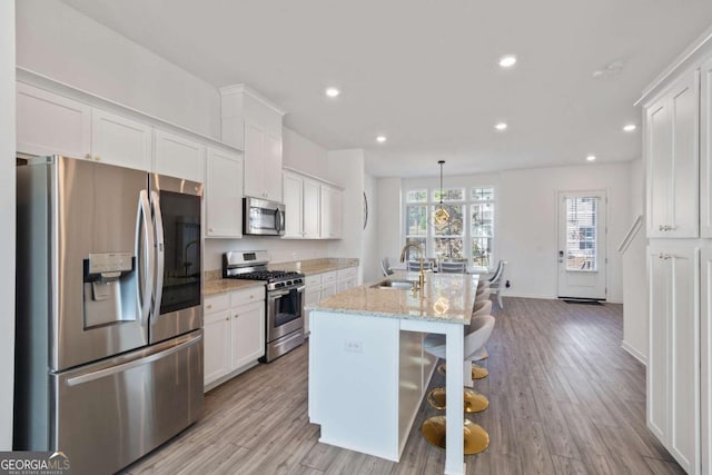 kitchen featuring an island with sink, white cabinetry, stainless steel appliances, and sink