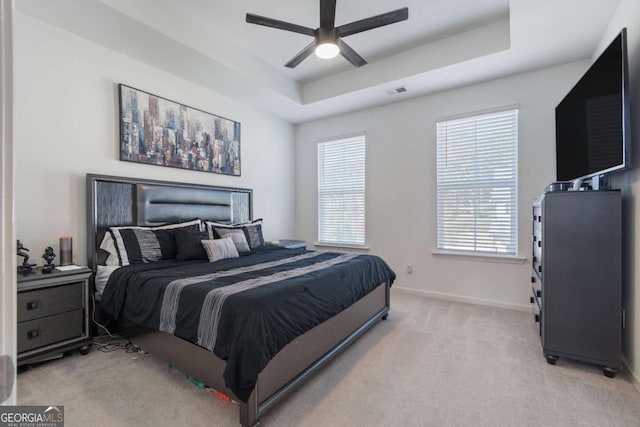 carpeted bedroom featuring a raised ceiling and ceiling fan