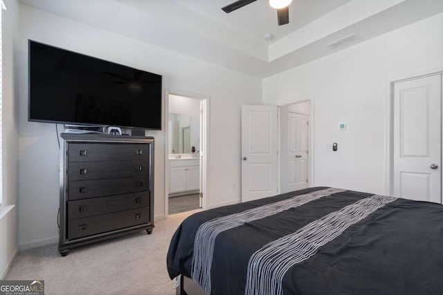 carpeted bedroom featuring ceiling fan, a raised ceiling, and connected bathroom