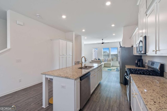 kitchen featuring white cabinetry, a center island with sink, light stone countertops, sink, and appliances with stainless steel finishes