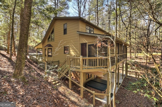 back of property featuring stairs, a wooden deck, and a sunroom