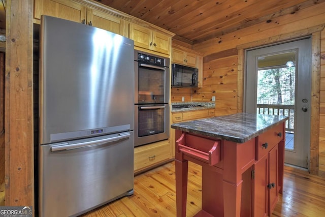 kitchen featuring dark stone counters, wood ceiling, a center island, wood walls, and black appliances