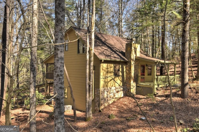 view of home's exterior with a balcony, a chimney, a porch, and roof with shingles