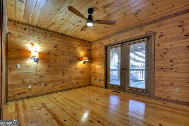 entryway featuring french doors, light wood finished floors, visible vents, wood ceiling, and wooden walls