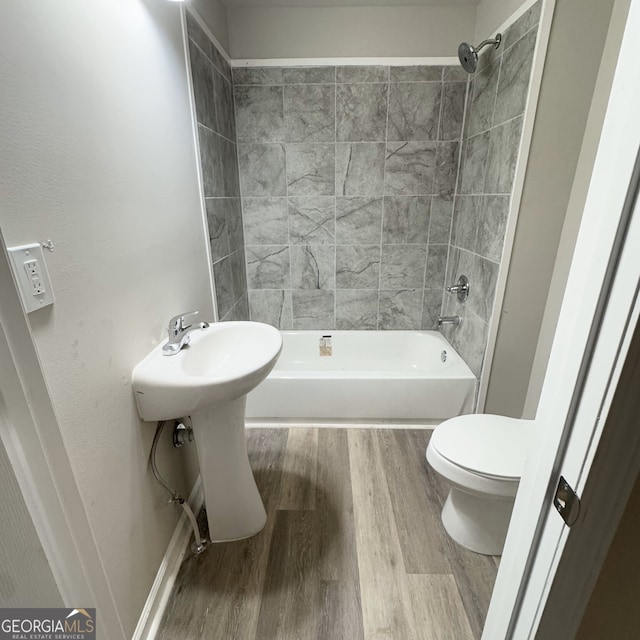 bathroom with toilet, hardwood / wood-style flooring, and tiled shower