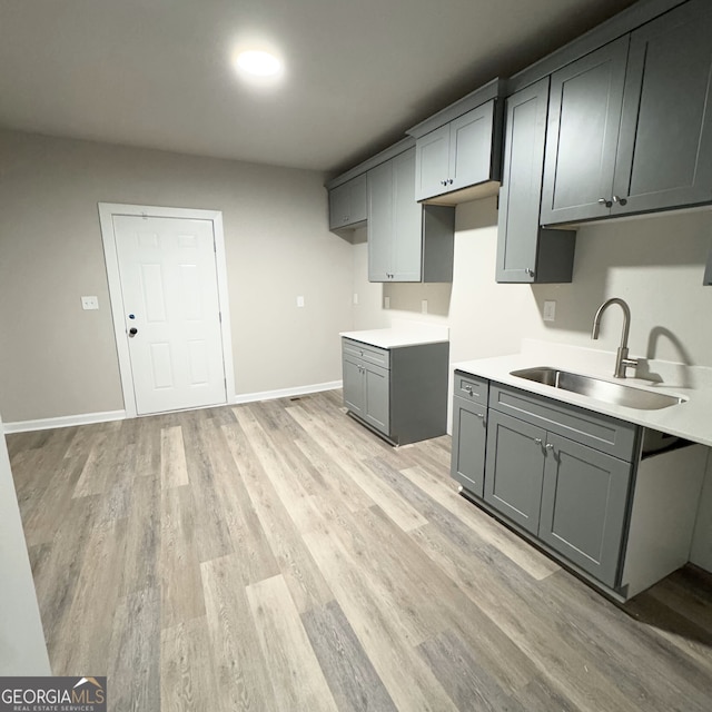 kitchen with light hardwood / wood-style floors, sink, and gray cabinetry