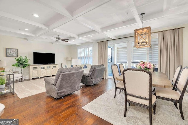 dining room with beam ceiling, ceiling fan with notable chandelier, dark wood-type flooring, and coffered ceiling