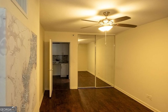 unfurnished bedroom with dark hardwood / wood-style flooring, ceiling fan, and a closet