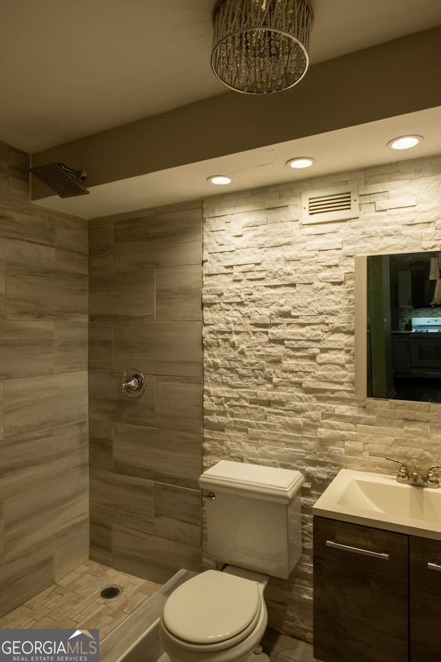 bathroom with vanity, a tile shower, and toilet