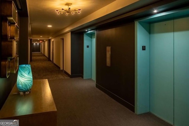 hall with elevator and dark colored carpet