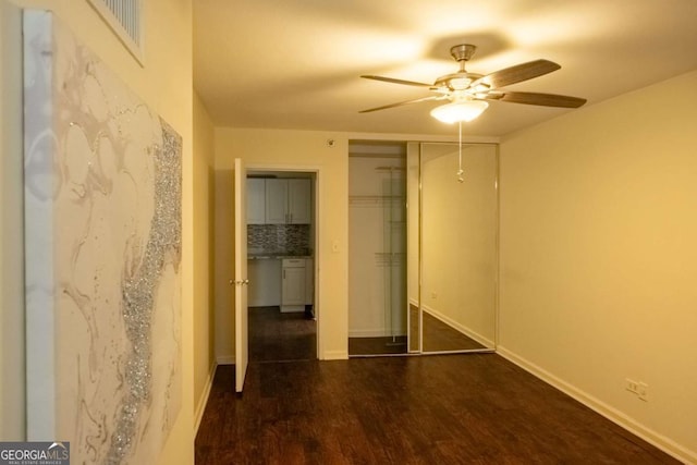 unfurnished bedroom featuring ceiling fan, a closet, and dark wood-type flooring