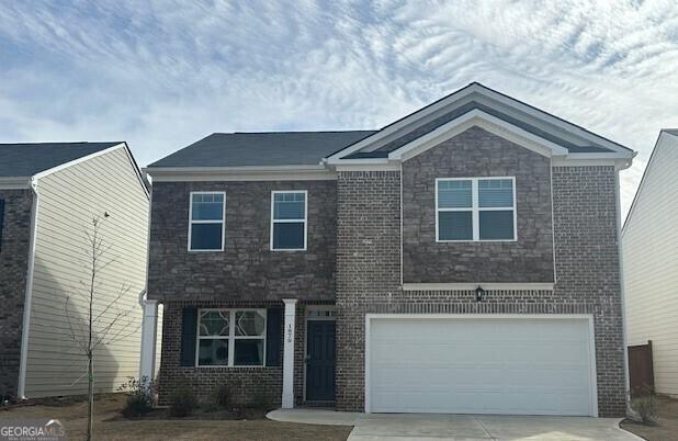 view of front of home with a garage, concrete driveway, and brick siding