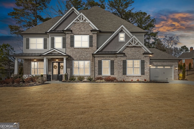 craftsman-style house featuring an attached garage, brick siding, a standing seam roof, and a front yard