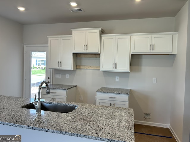 9 Wildflower Ln Unit 41, Dallas, GA 30132 - kitchen featuring light stone countertops, white cabinets, a sink, baseboards, and recessed lighting