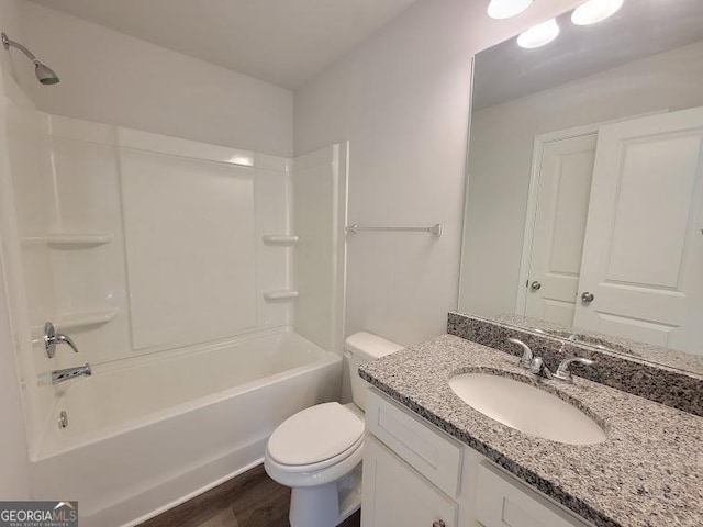 full bathroom with hardwood / wood-style floors, vanity, toilet, and washtub / shower combination