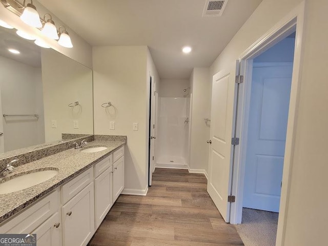 bathroom with a shower, hardwood / wood-style flooring, and vanity