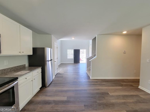 kitchen with appliances with stainless steel finishes, dark stone countertops, dark wood-type flooring, and white cabinets