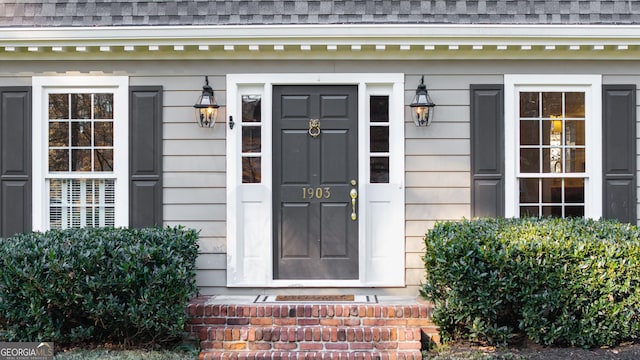 entrance to property featuring a shingled roof