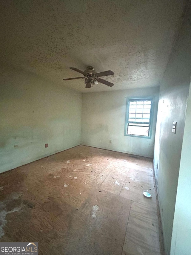 empty room with ceiling fan and a textured ceiling