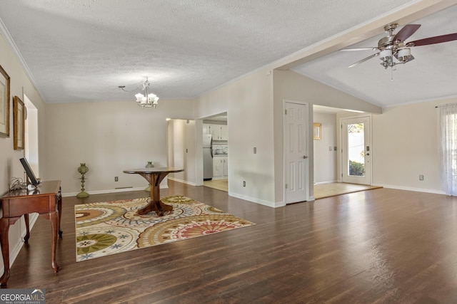 interior space with ceiling fan with notable chandelier, a textured ceiling, lofted ceiling, dark hardwood / wood-style flooring, and ornamental molding