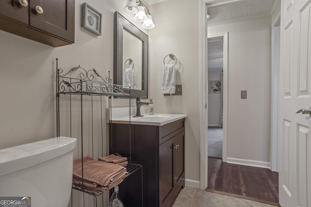 bathroom with toilet, a textured ceiling, vanity, and ornamental molding