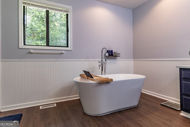 bathroom with vanity, wood-type flooring, and a tub to relax in