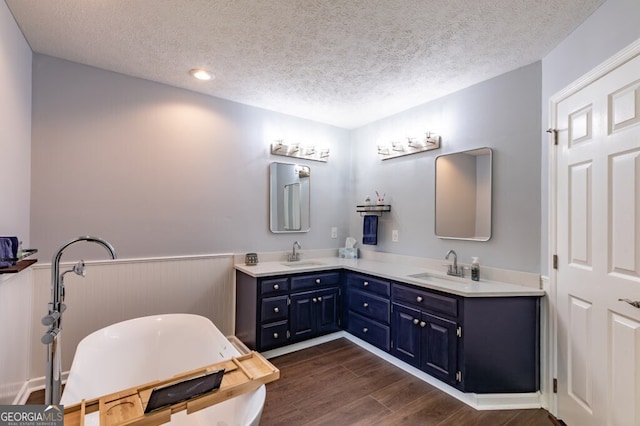 bathroom featuring vanity, a bathtub, wood-type flooring, and a textured ceiling