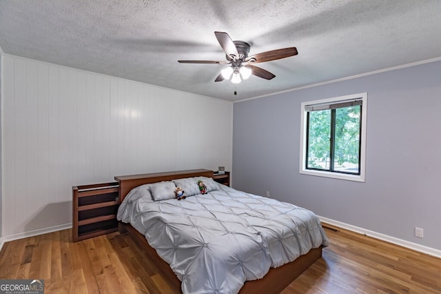 bedroom with ceiling fan, ornamental molding, a textured ceiling, and hardwood / wood-style floors