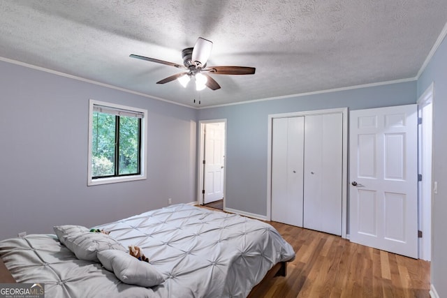 bedroom featuring a textured ceiling, a closet, crown molding, and wood-type flooring