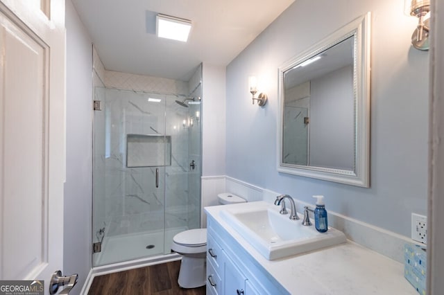 bathroom featuring hardwood / wood-style floors, vanity, a shower with shower door, and toilet