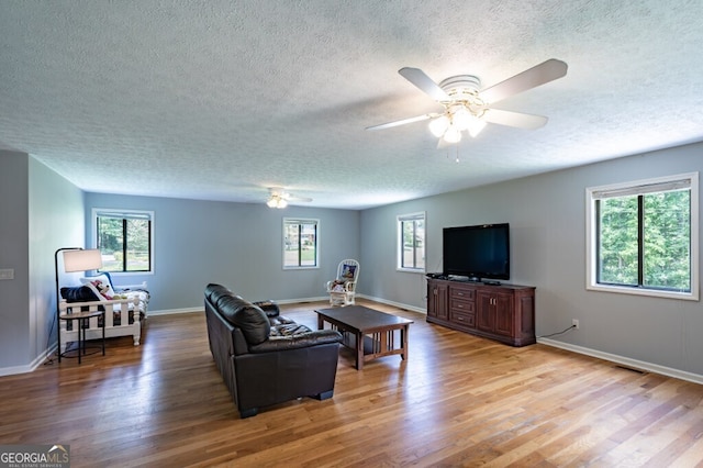 living room featuring ceiling fan, light hardwood / wood-style floors, a textured ceiling, and a wealth of natural light