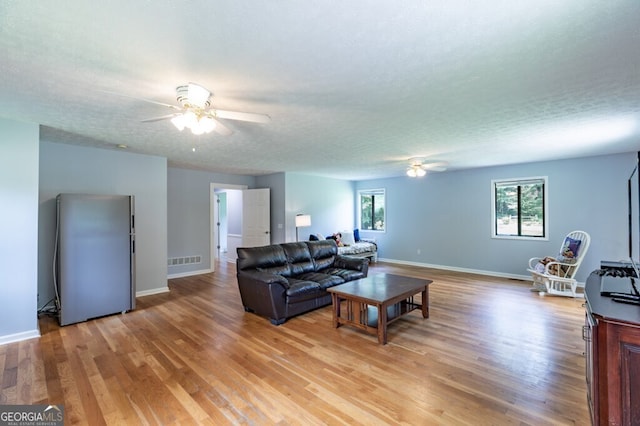 living room featuring a textured ceiling, light hardwood / wood-style floors, and ceiling fan