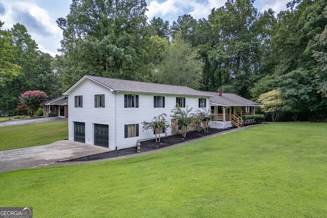 rear view of property featuring covered porch, a garage, and a lawn