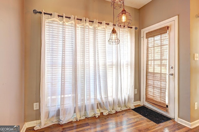 doorway featuring baseboards and wood finished floors