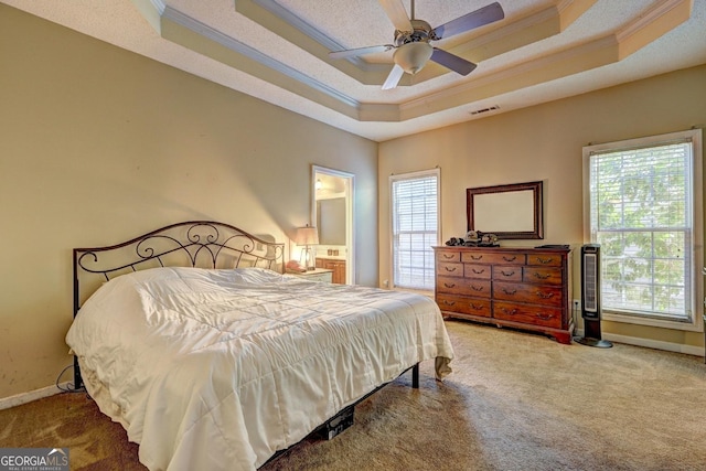 carpeted bedroom with visible vents, a tray ceiling, baseboards, and ornamental molding