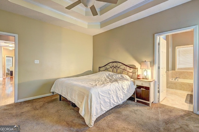 bedroom with ensuite bathroom, light colored carpet, baseboards, ornamental molding, and a raised ceiling