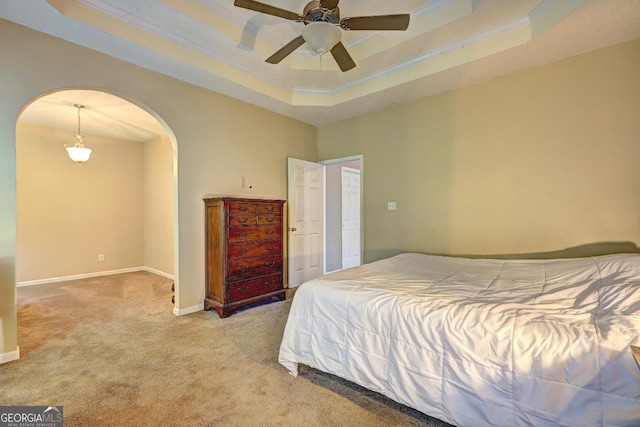 bedroom featuring arched walkways, a tray ceiling, crown molding, and light colored carpet