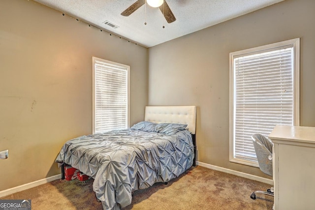 bedroom with baseboards, a textured ceiling, visible vents, and light colored carpet