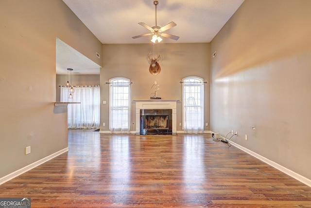 unfurnished living room with a high end fireplace, dark wood-style flooring, plenty of natural light, and baseboards