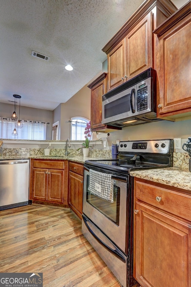 kitchen featuring stainless steel appliances, light wood-type flooring, and brown cabinets