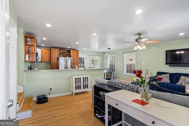 kitchen featuring stainless steel refrigerator, light hardwood / wood-style flooring, ceiling fan, and kitchen peninsula