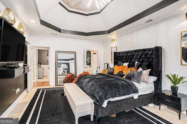 bedroom featuring light wood-type flooring and a raised ceiling