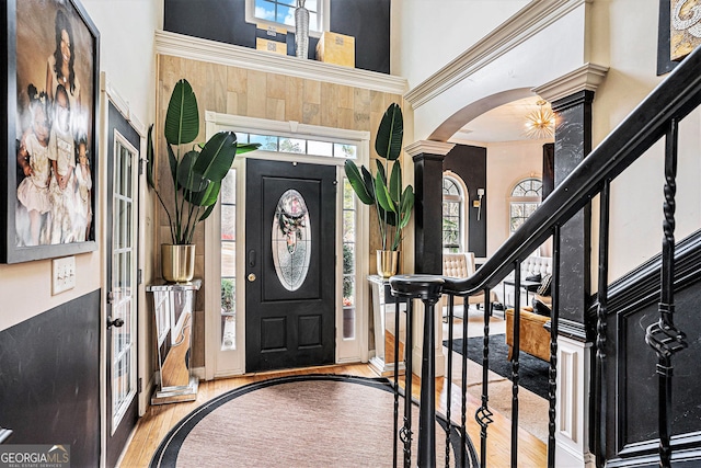 entryway with decorative columns, a towering ceiling, and light hardwood / wood-style floors