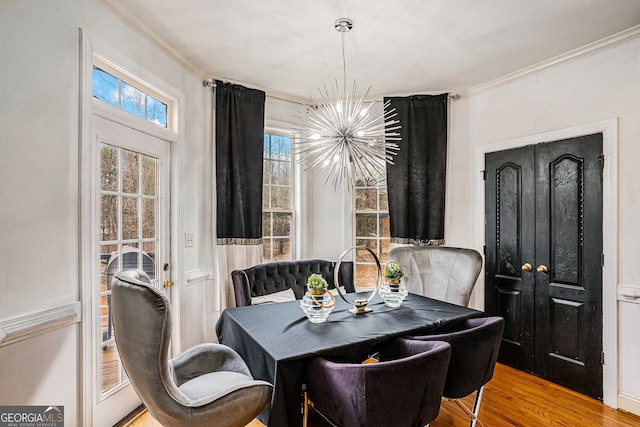 dining space with ornamental molding, an inviting chandelier, and wood-type flooring