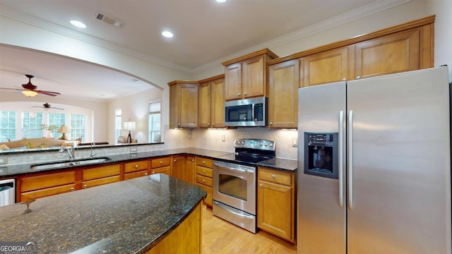 kitchen featuring stainless steel appliances, light hardwood / wood-style flooring, sink, dark stone countertops, and crown molding