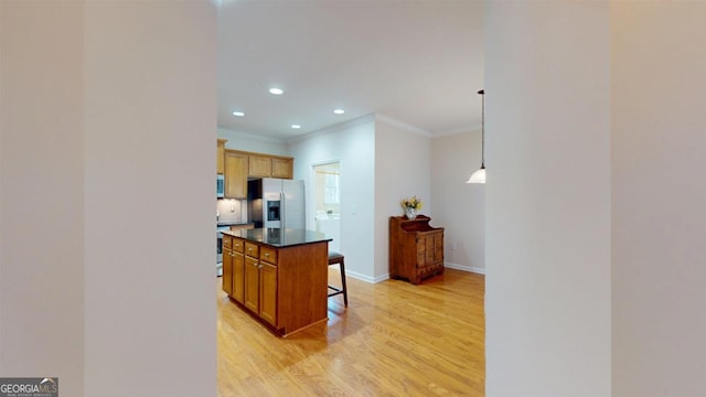 kitchen featuring stainless steel appliances, light hardwood / wood-style floors, pendant lighting, a breakfast bar, and a kitchen island