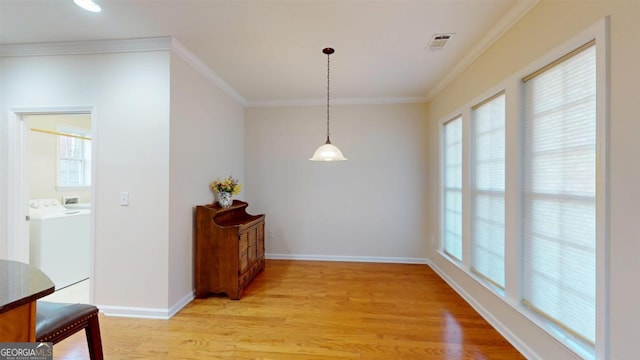 dining space with ornamental molding, separate washer and dryer, and light hardwood / wood-style flooring