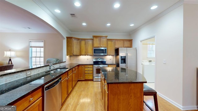 kitchen with dark stone countertops, appliances with stainless steel finishes, sink, kitchen peninsula, and a breakfast bar area