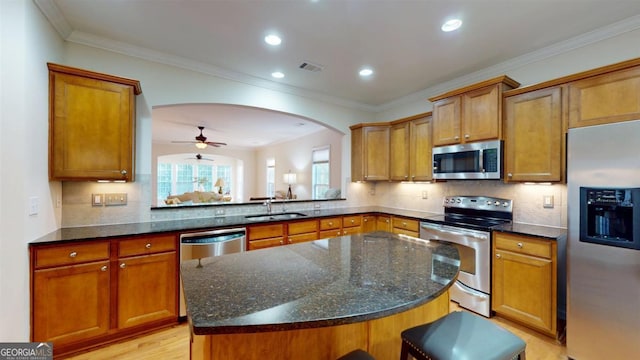 kitchen with a center island, sink, dark stone counters, appliances with stainless steel finishes, and decorative backsplash